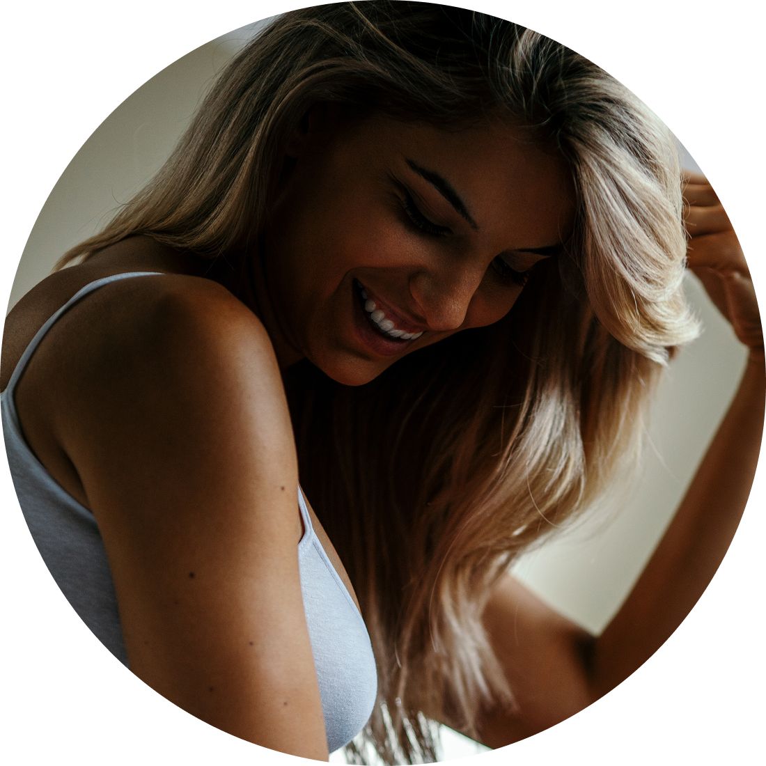 Woman with curly hair outdoors at sunset.